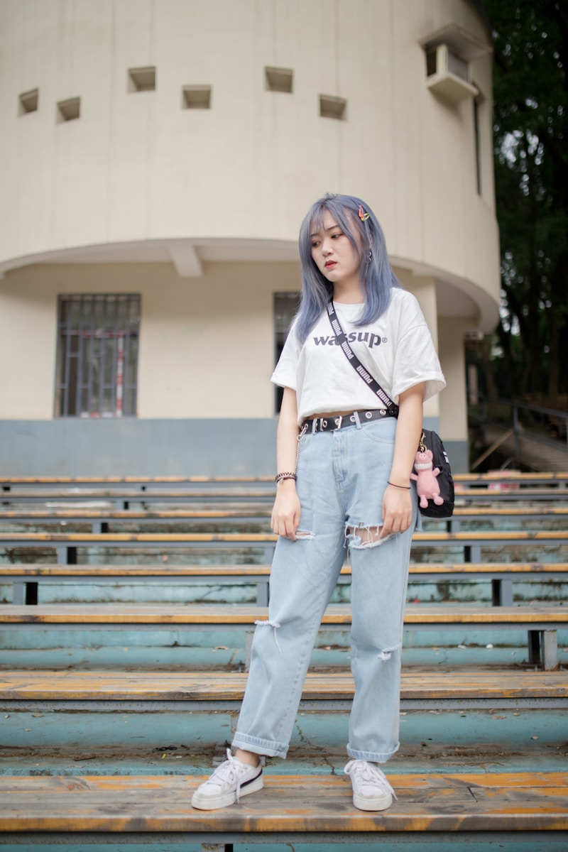 woman in white t-shirt and blue denim jeans standing on brown wooden bench during daytime