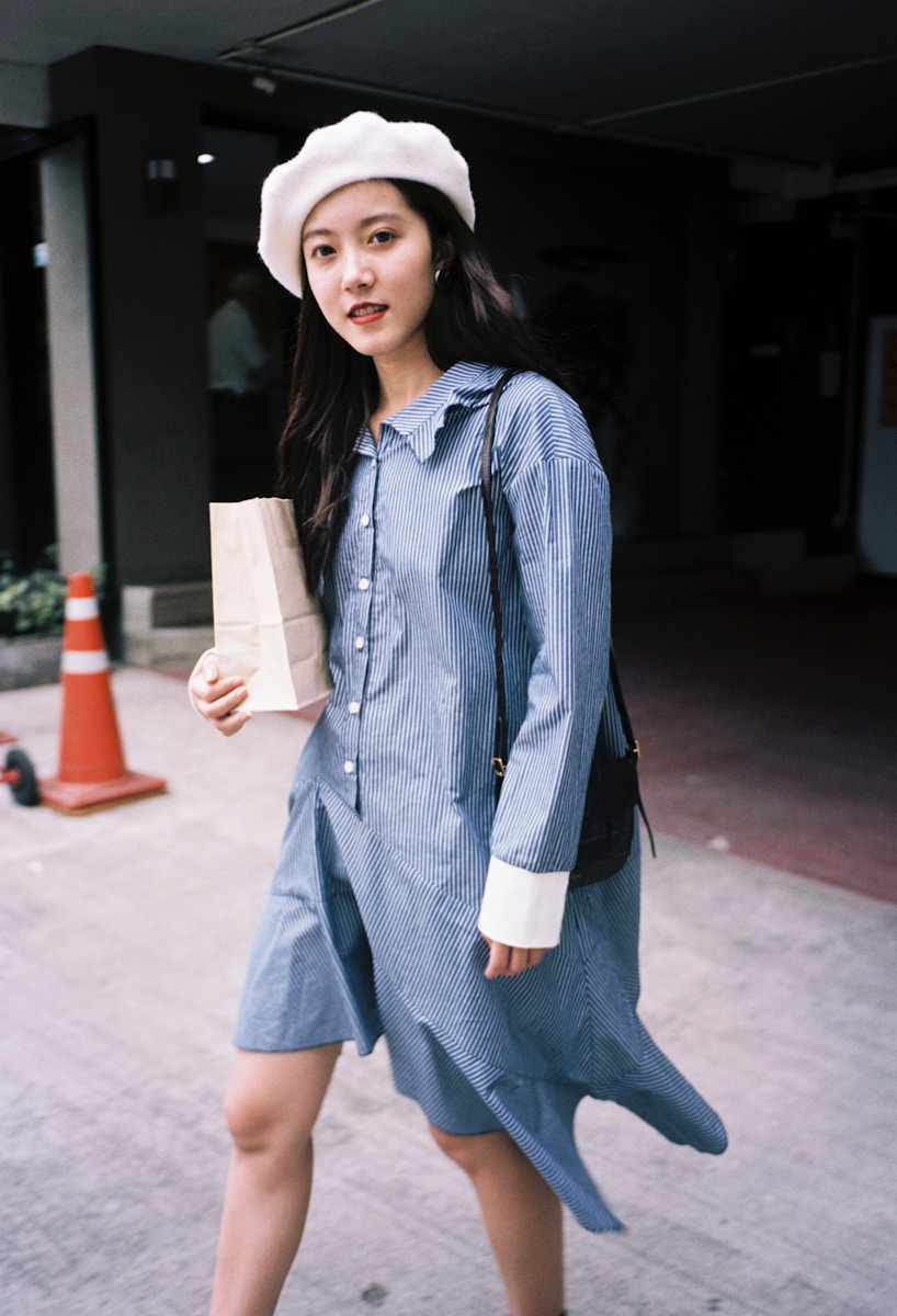 a woman in a dress and hat walking down the street