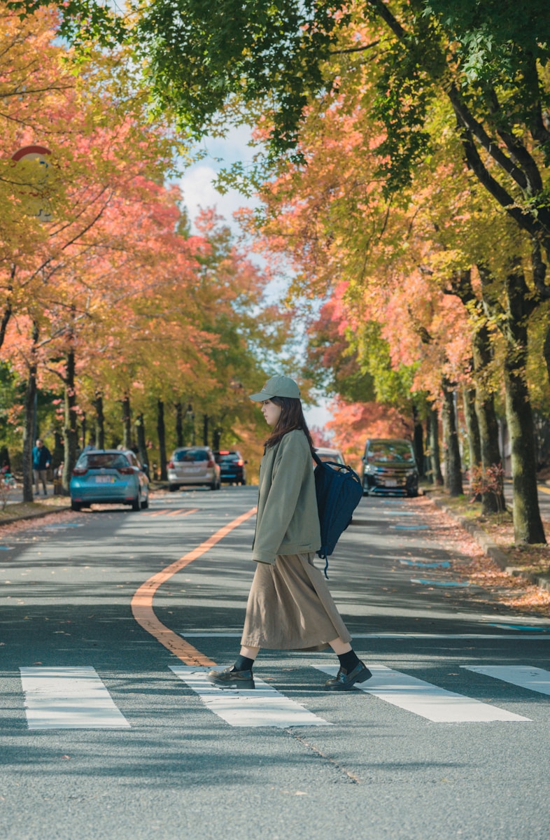 A woman walking across a street with a backpack