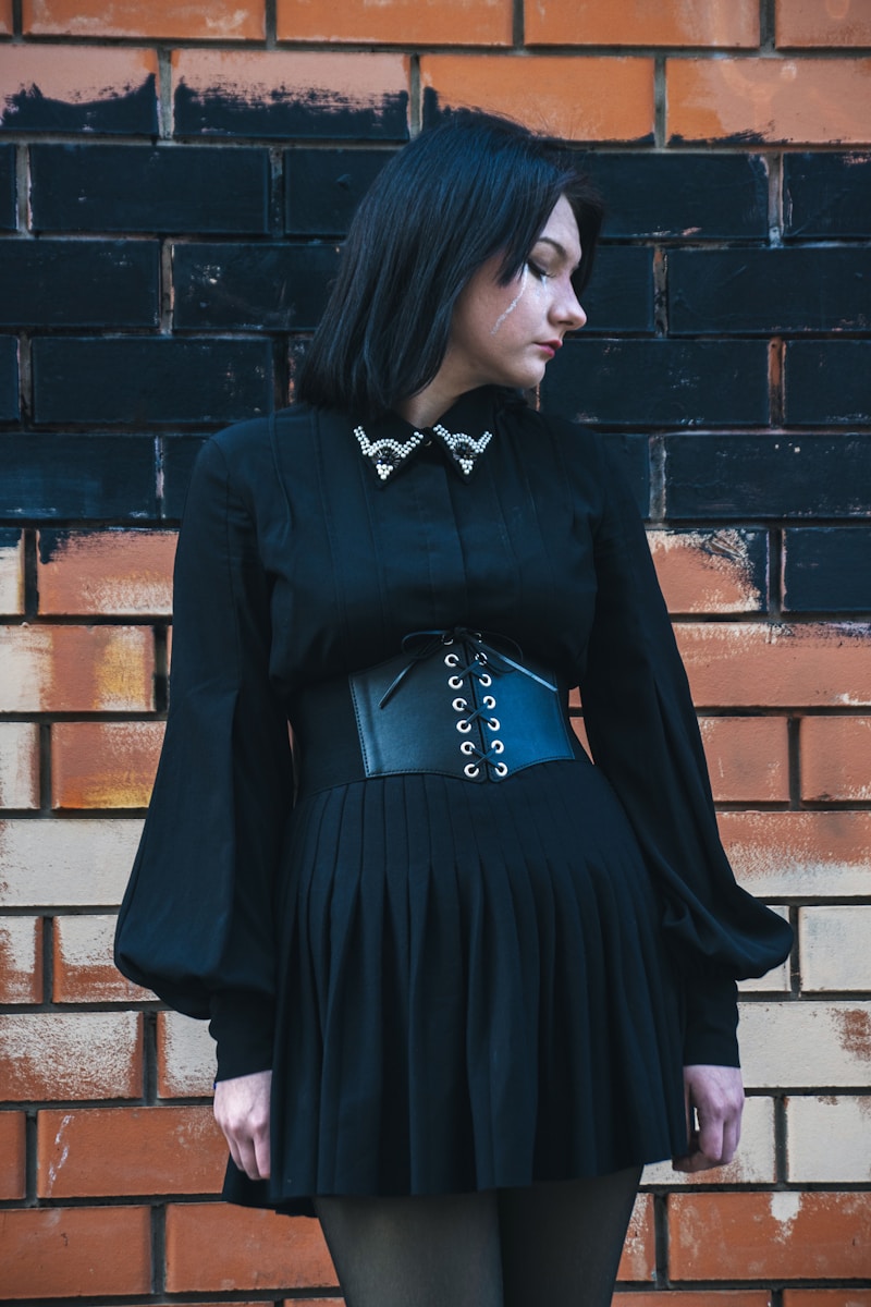 A woman poses in a black gothic outfit.